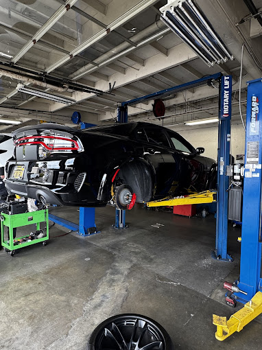 Black car on lift in auto repair shop with tools and equipment