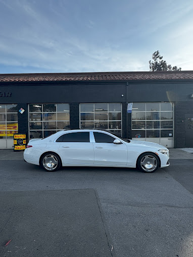 White luxury sedan parked in front of a modern automotive service center