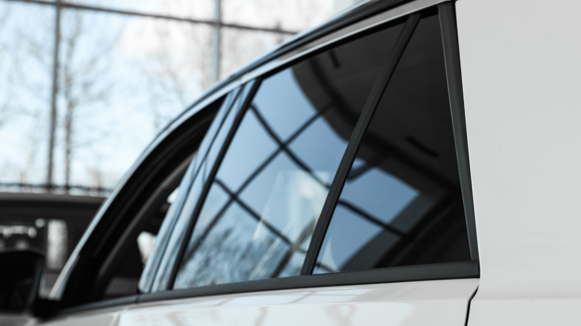 Close-up of car window with reflective glass and geometric window frame