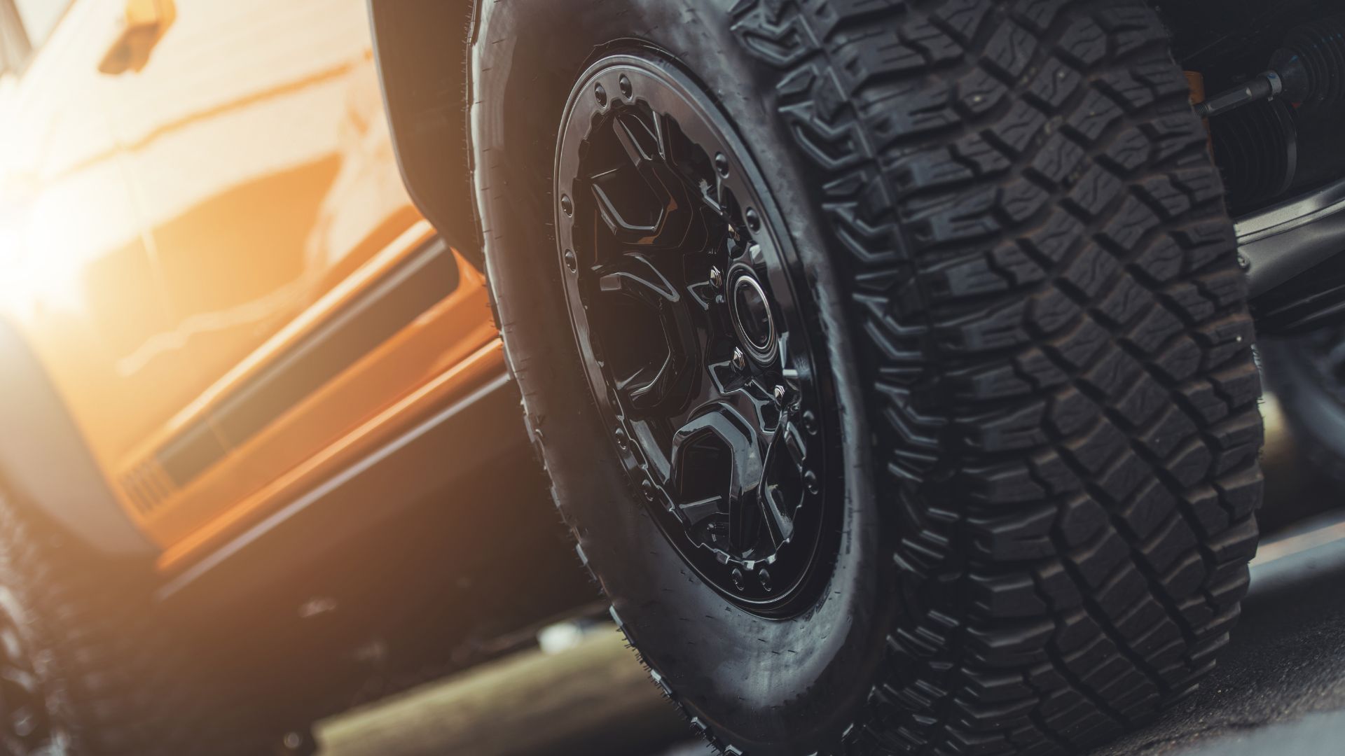 Off-road tire with rugged tread mounted on black wheel with sunlight