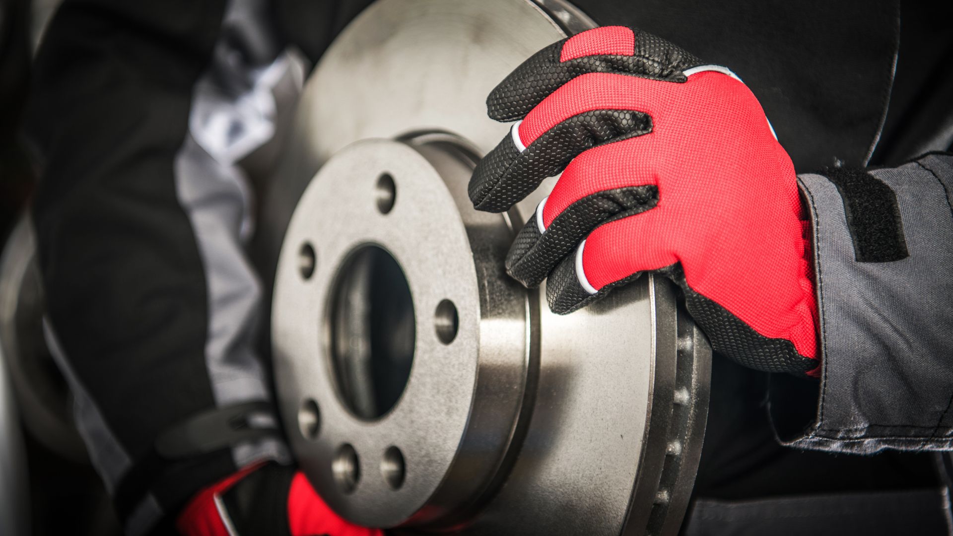 Red and black gloved hand inspecting car brake disc