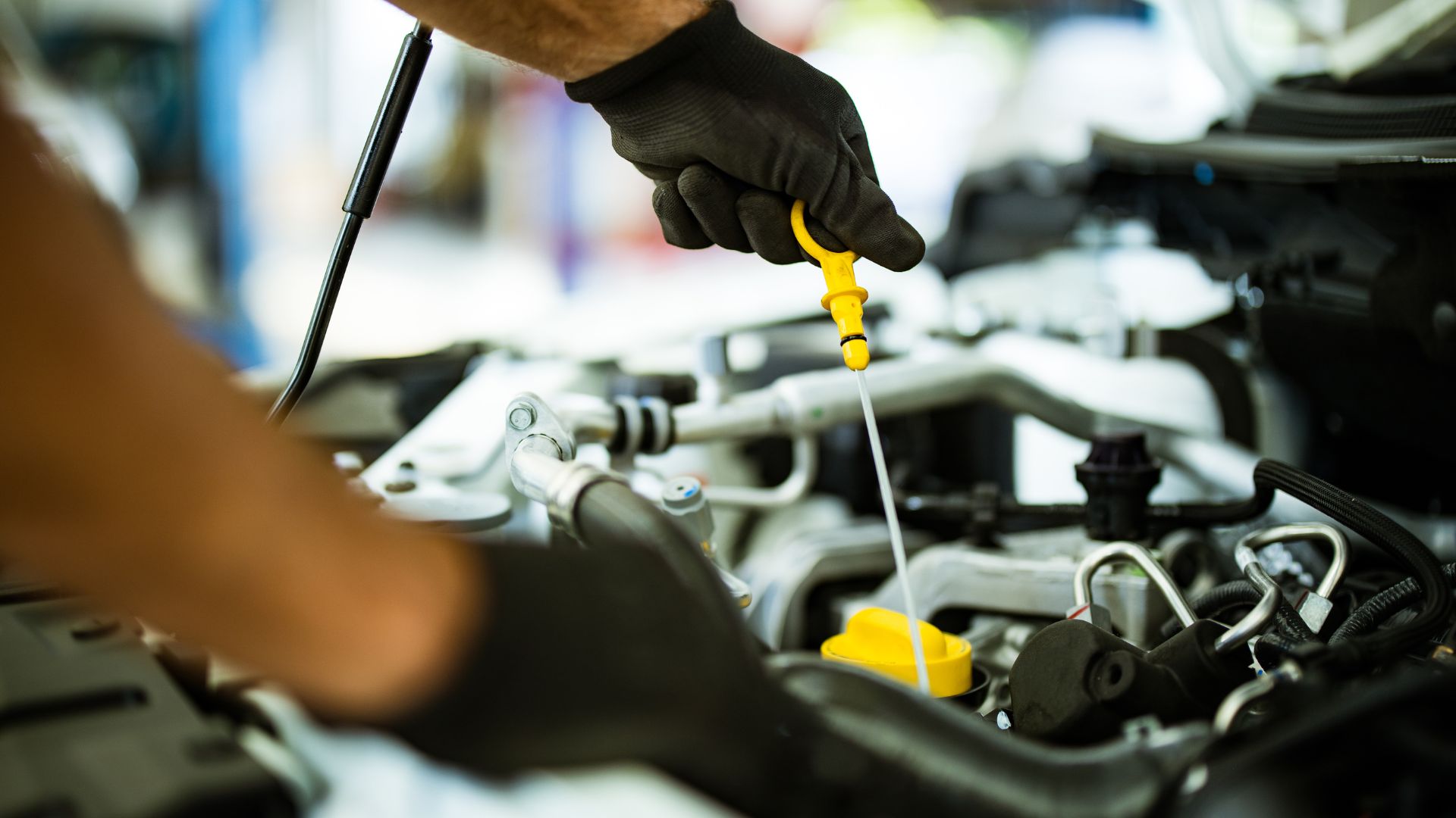 Mechanic checking oil level in car engine with dipstick