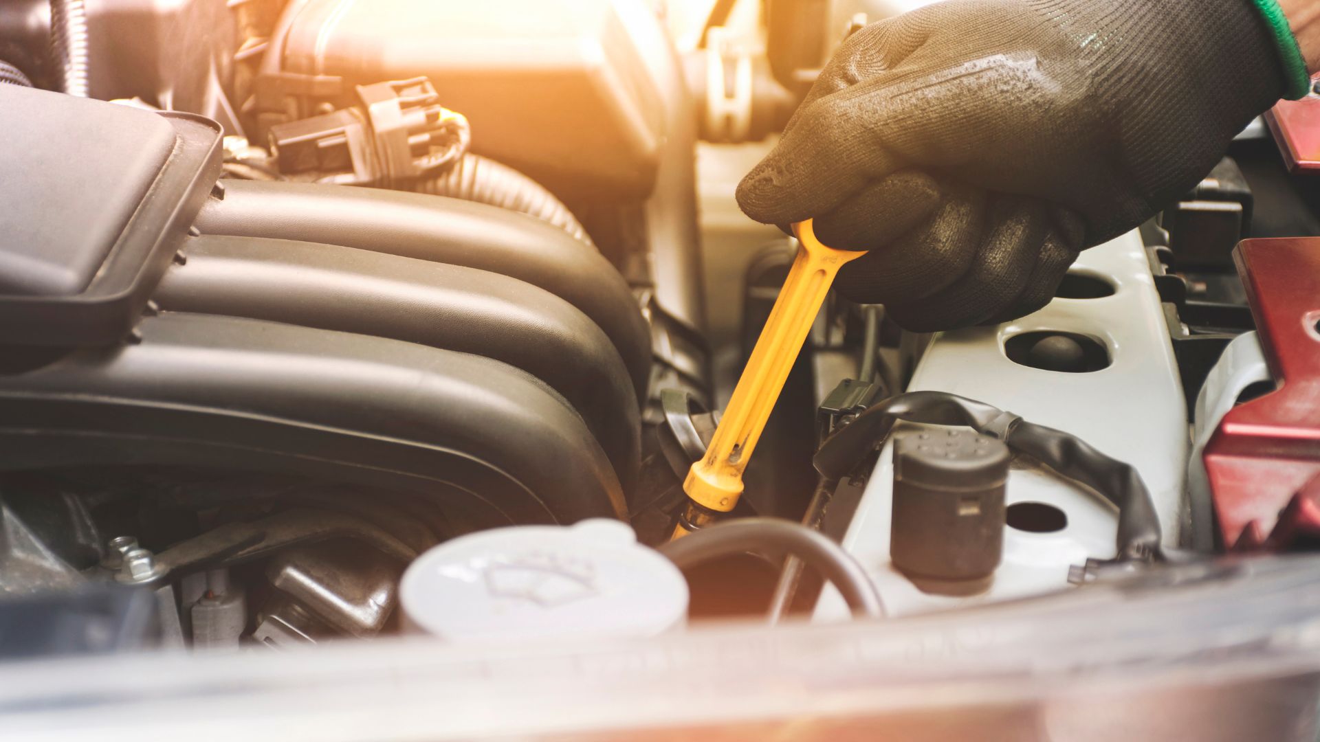 Mechanic checking car engine oil level with yellow dipstick